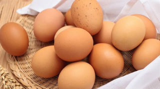 A dozen brown eggs in a wicker basket
